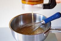 Liquid being poured into a mixing bowl containing a whisk