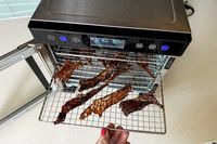 The Magic Mill food dehydrator with racks full of beef jerky