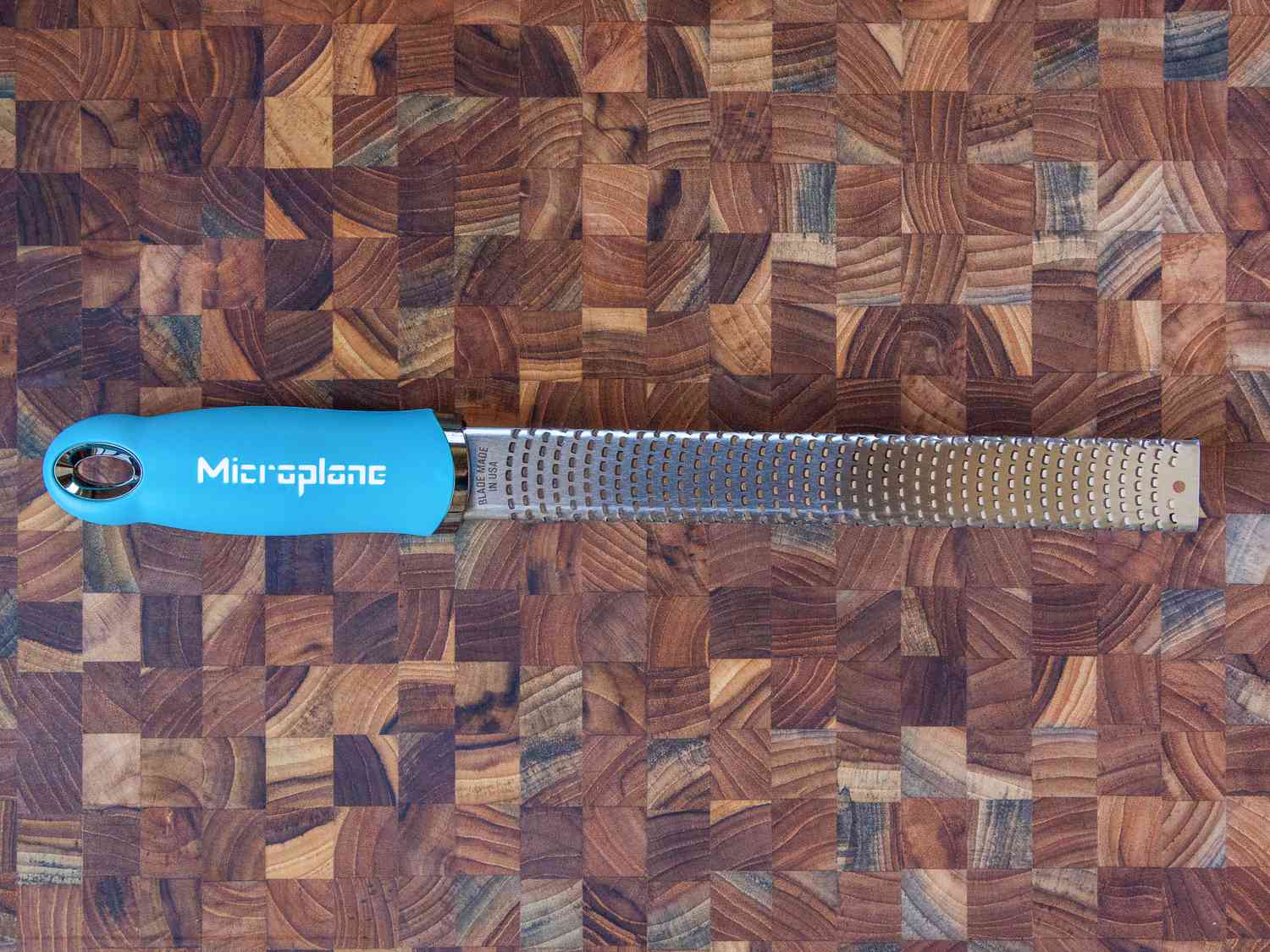 blue-handled microplane grater on a wooden surface