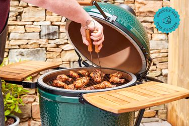 A Big Green Egg kamado smoker loaded with chicken wings.
