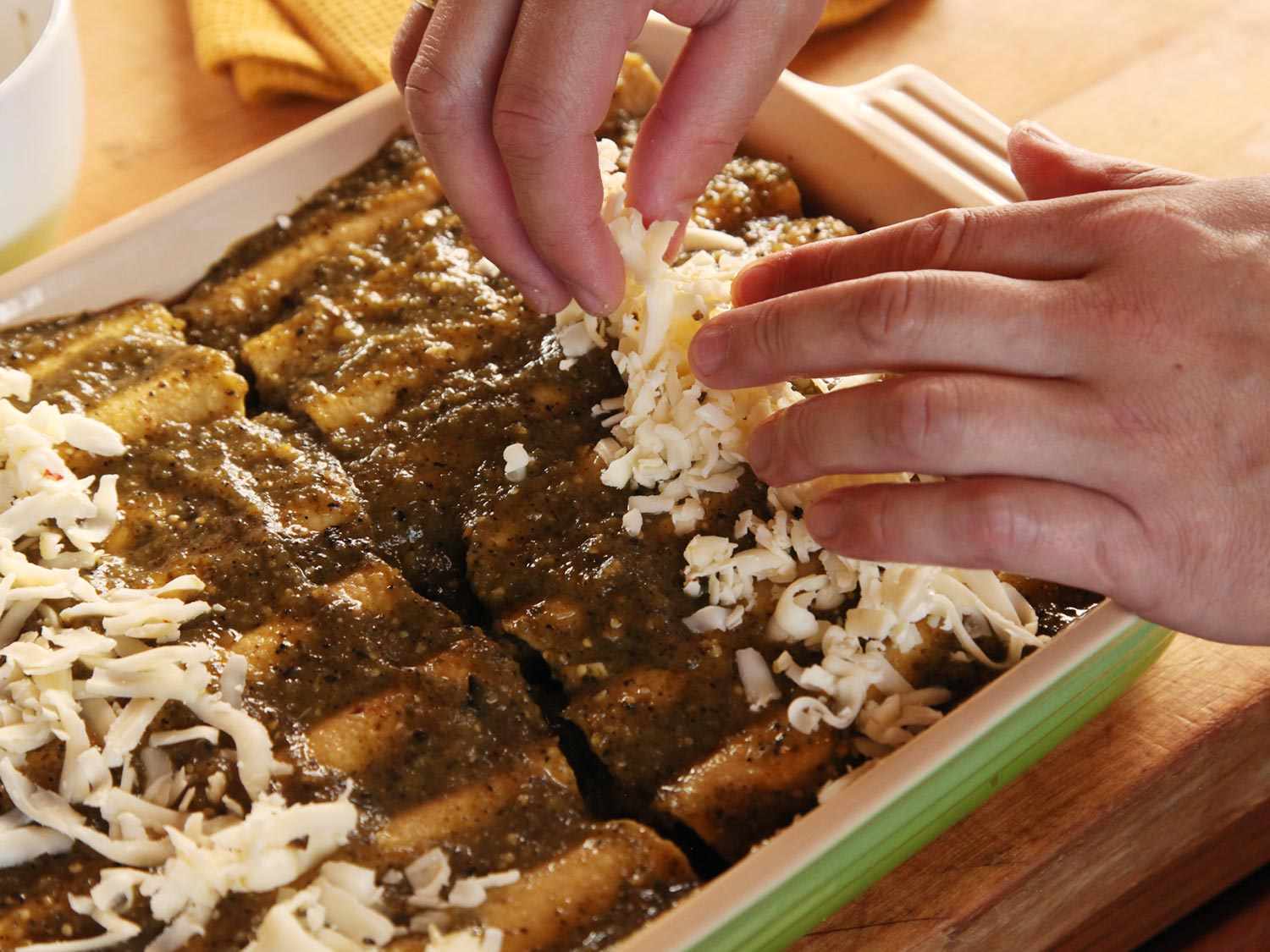 Shredded pepper jack is sprinkled over the sauced enchiladas.