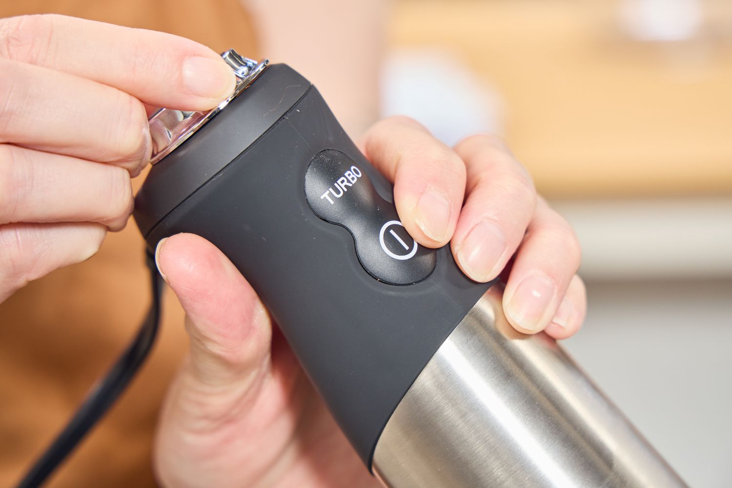A person adjusts the dial on the All-Clad Stainless Steel Immersion Blender