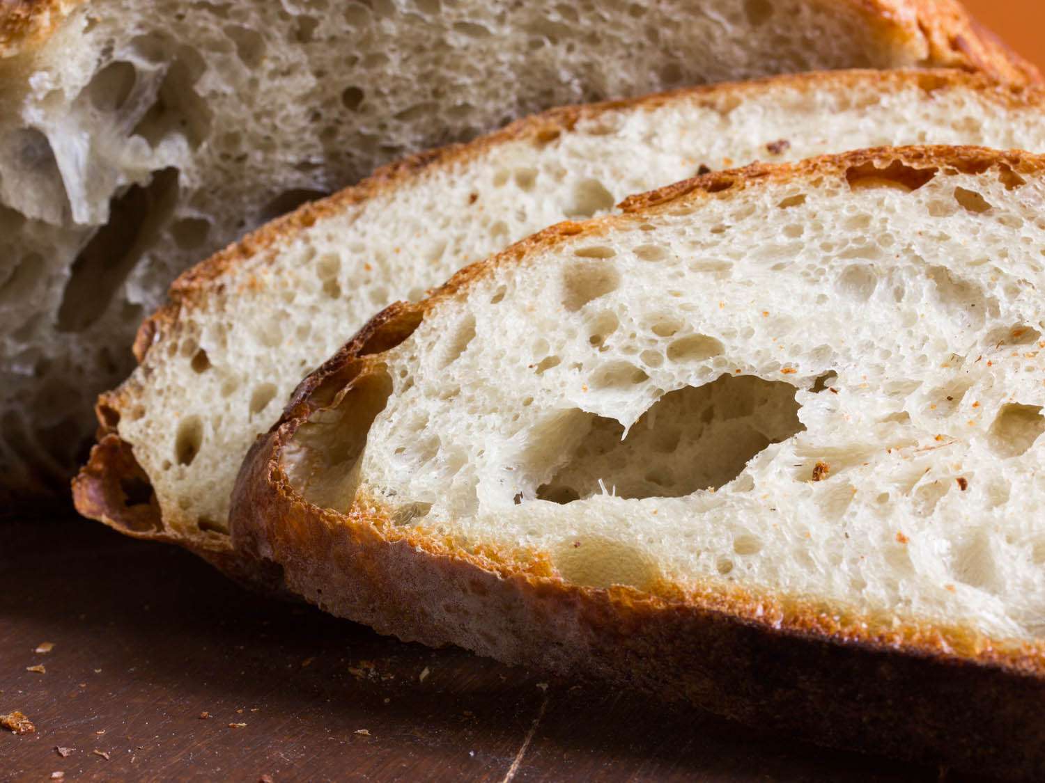 A close up of two slices of artisanal bread, with the rest of the loaf in the background.