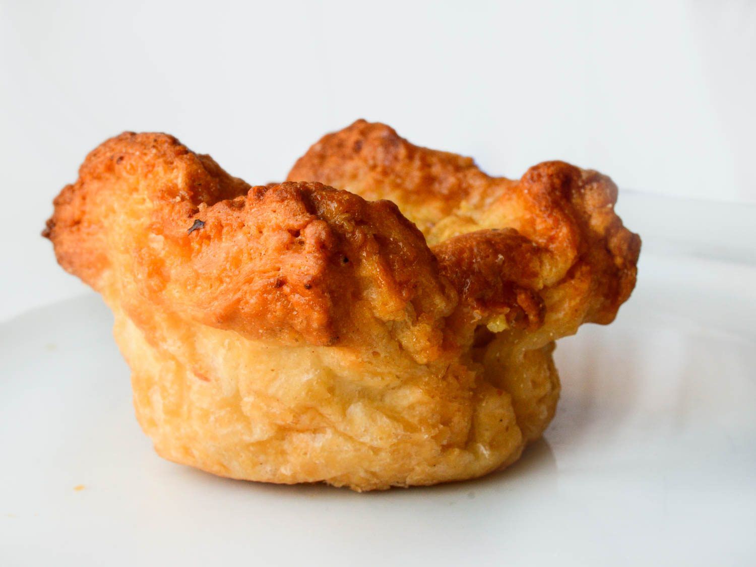 Side view of kouign amann pastry on white background.
