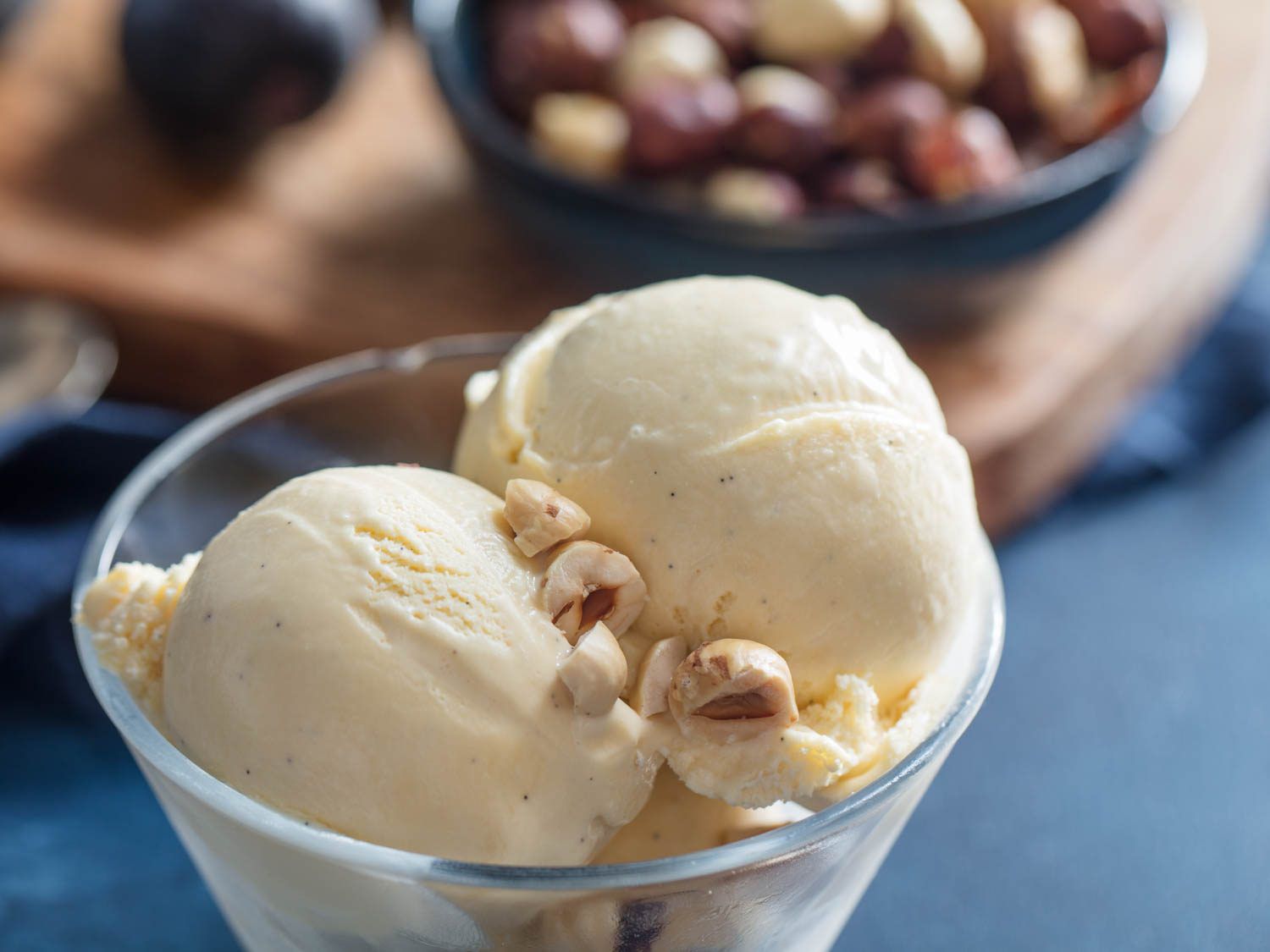 Two scoops of hazelnut ice cream in a serving bowl, garnished with chopped hazelnuts.
