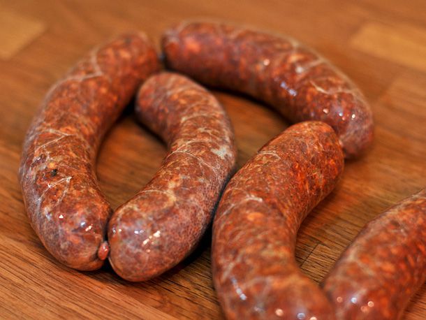 Finished sausage links on a wooden work surface.