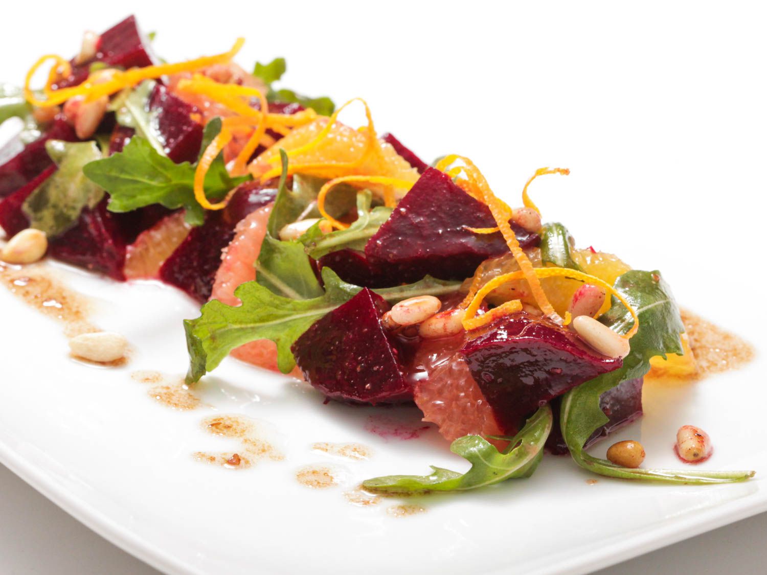 Roasted beet and citrus salad with arugula and pine nuts on a plate.