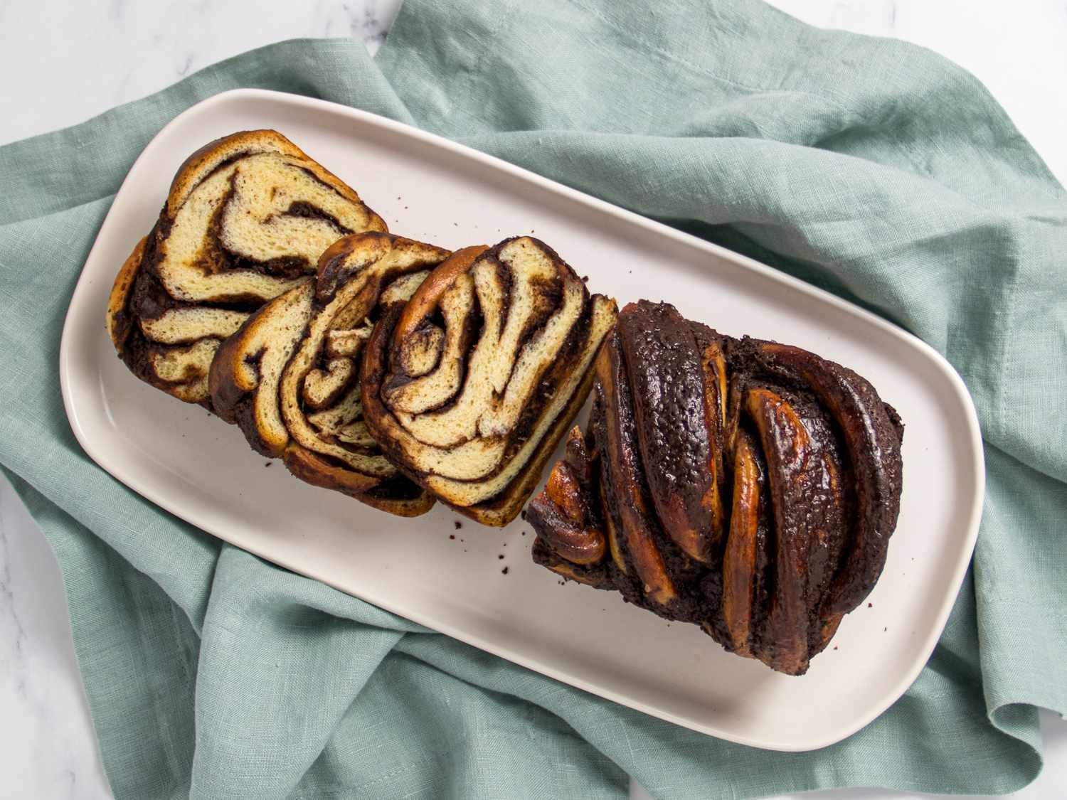 Sliced babka on a white plate, on top of a blue linen