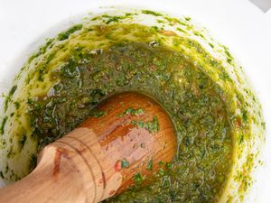 A mortar and pestle filled with a green herb-based sauce (pistou)