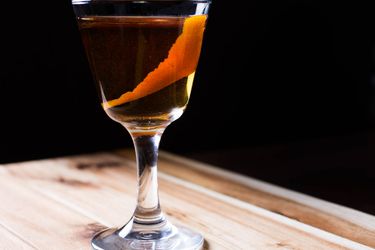 A three-ingredient cocktail called the Rob Roy garnished with a strip of orange peel.