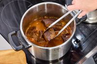 A pot of meat cooking in the T-Fal Clipso Pressure Cooker is stirred