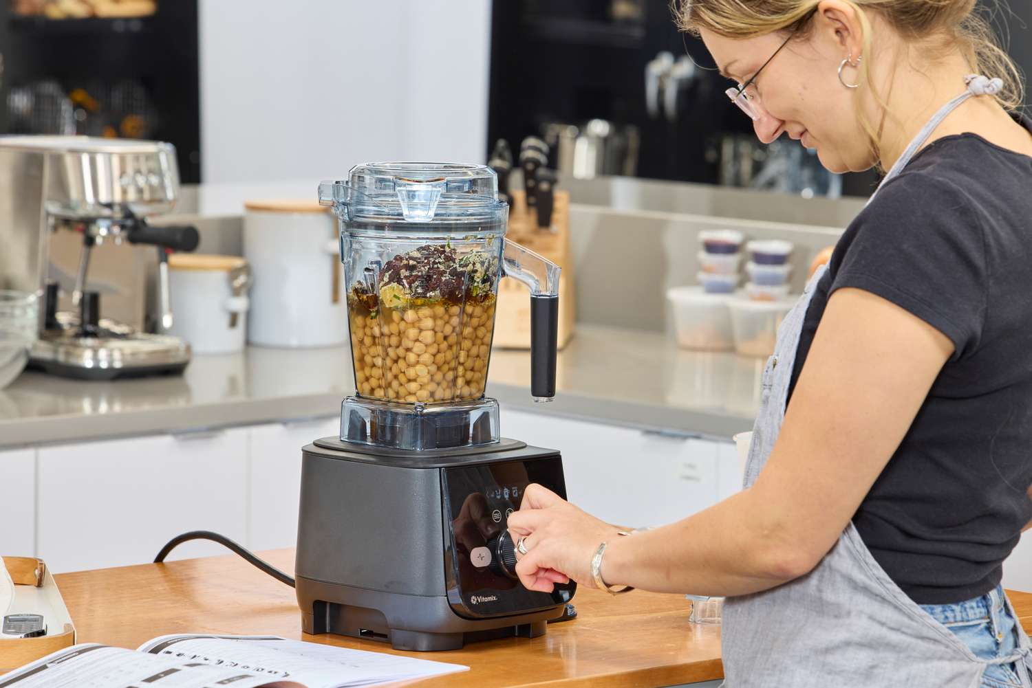 A person turning a nob on a filled Vitamix Ascent X5 Blender