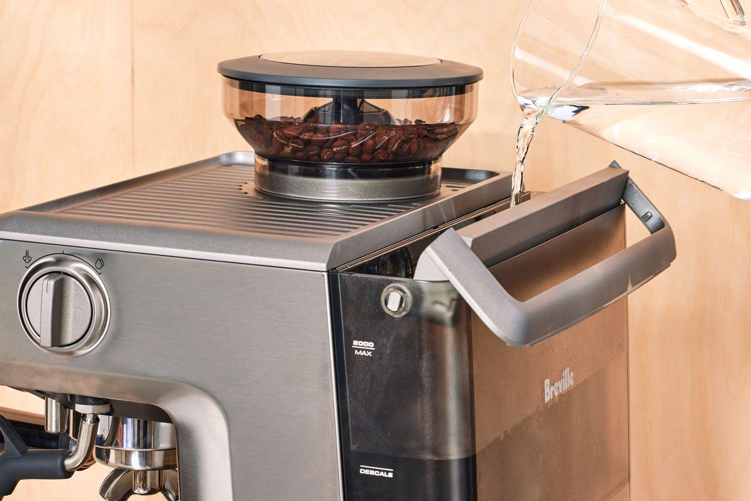 A person pouring in water into the container section of the Breville Barista Express Impress