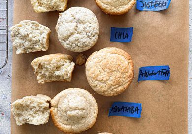 A comparison of muffins made with different egg substitutes labeled Egg Chia Aquafaba and Flax on parchment paper