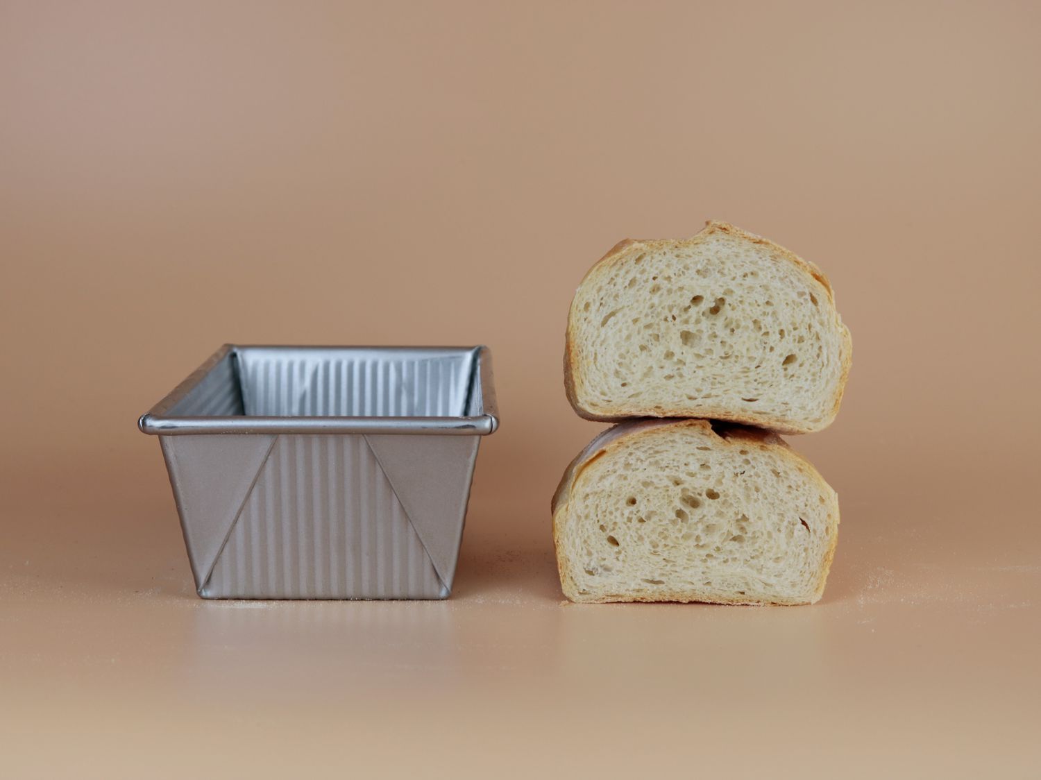 a loaf of bread cut in half next to a loaf pan