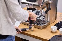 A person tamps ground espresso before adding it to the De'Longhi La Specialista Touch Espresso Machine