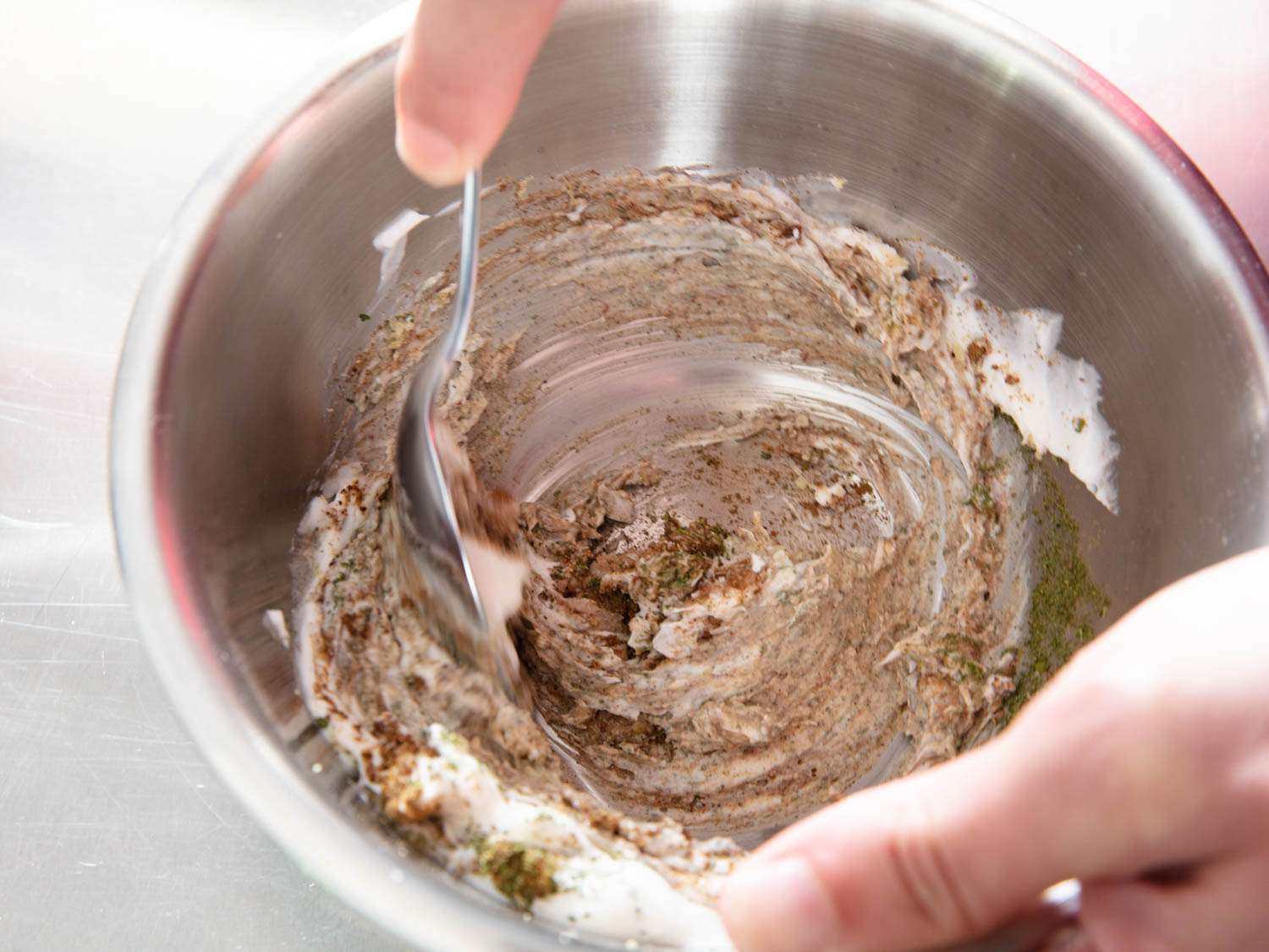 The yogurt marinade for the chicken is stirred together in a mixing bowl.