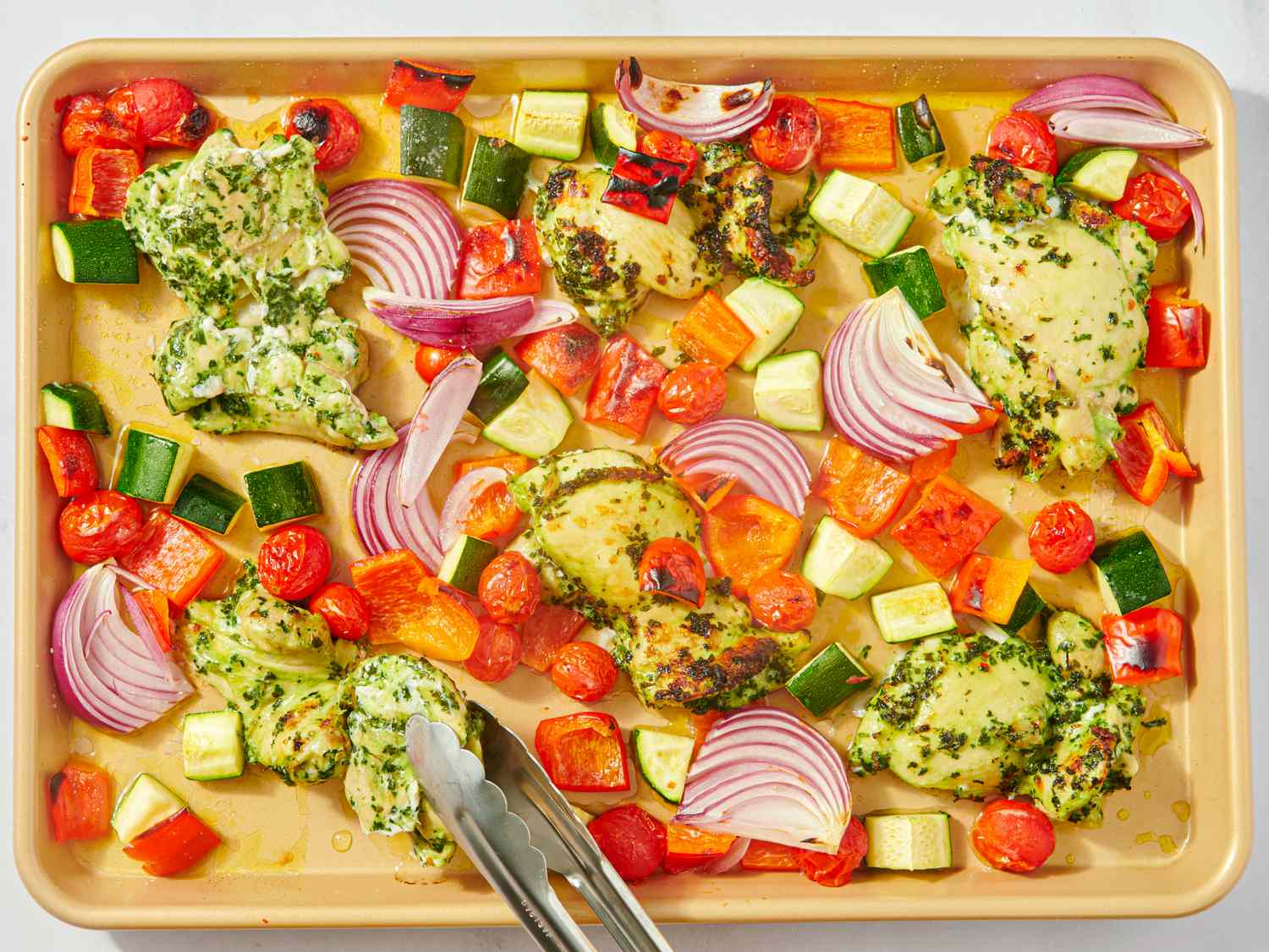 Baked chimichurri chicken thighs with vegetables on a baking sheet