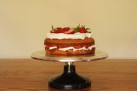 A decorated strawberry cake sits on a revolving cake stand made for decorating.