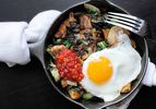 Overhead view of Spicy Potato, Bok Choy, and Shallot Hash, served in a cast iron skillet.