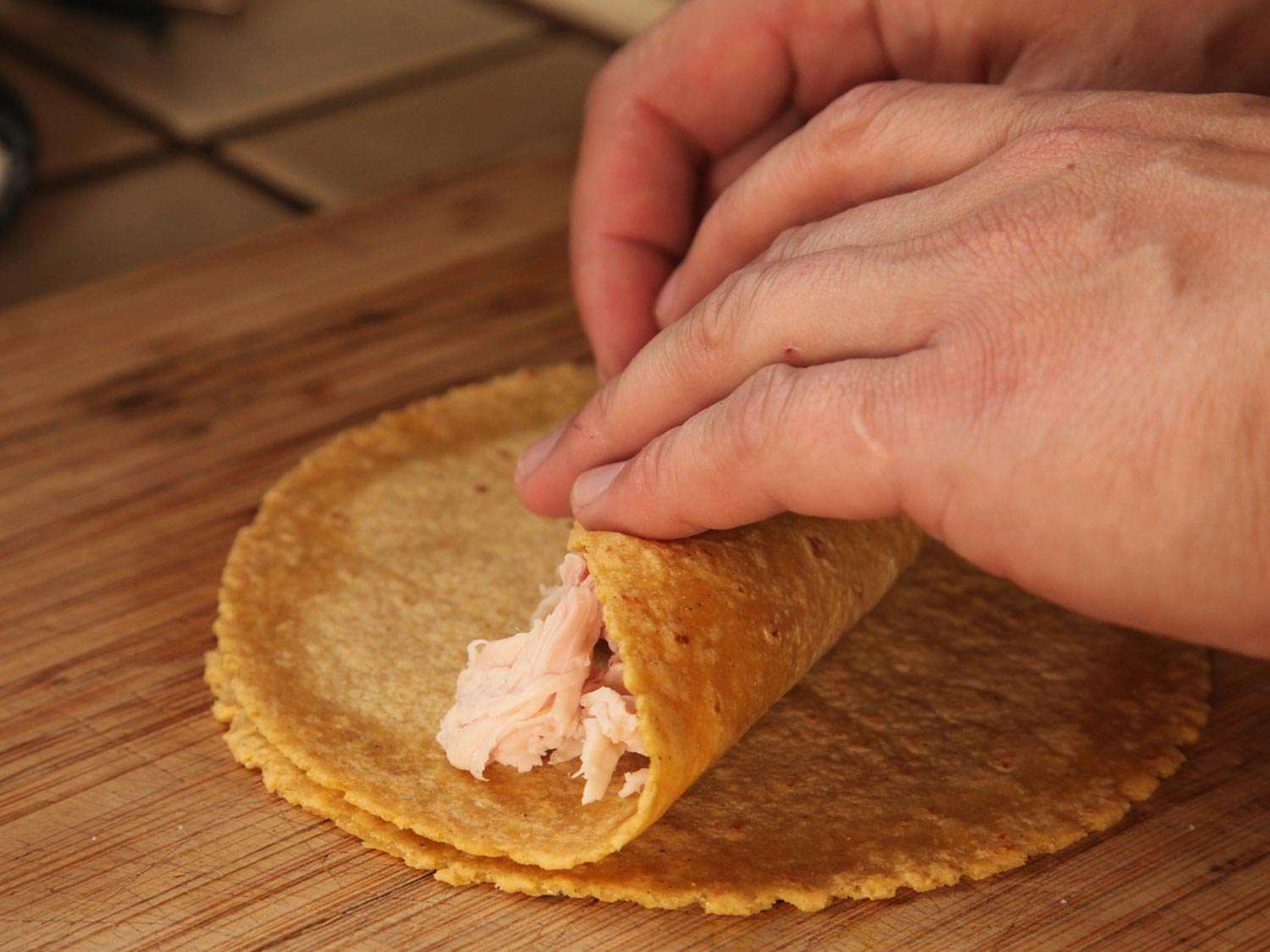 Rolling turkey in corn tortilla. 