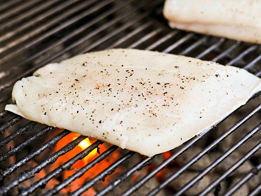 A seasoned halibut cooking on a grill