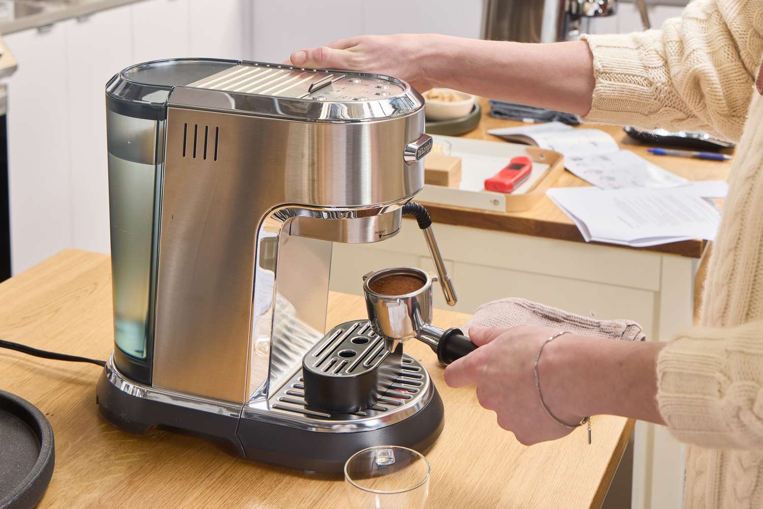 A person makes espresso using the De'Longhi EC900M Dedica Maestro Espresso Machine