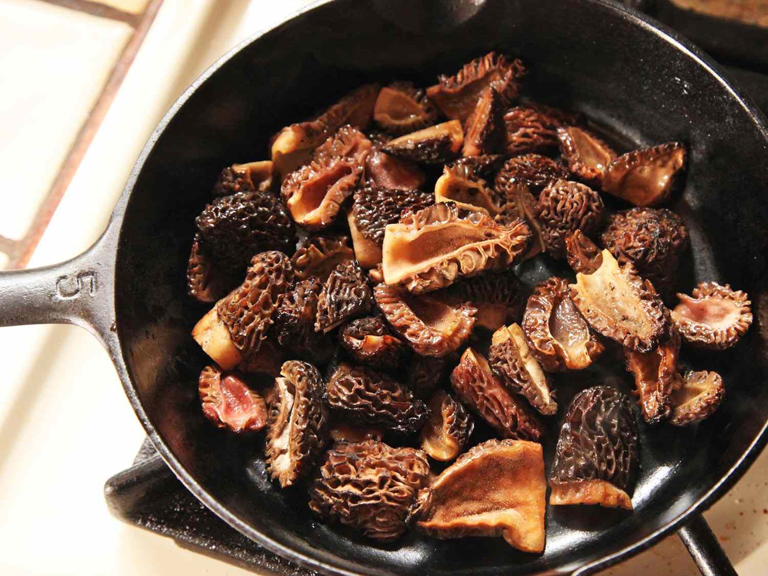 Morel mushrooms in a cast iron pan on the stove.