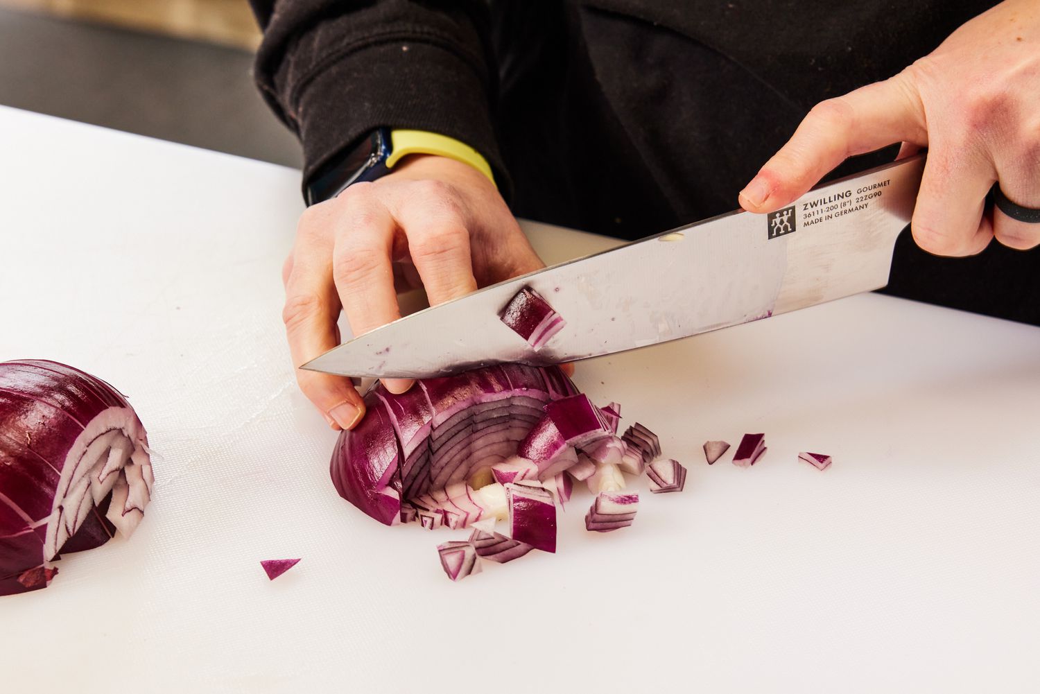 A person chops a red onion using a Zwilling Gourmet 10-Piece Knife Block Set knife