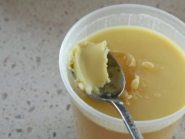 A spoon scooping off fat from the surface of the pork/chicken broth. 