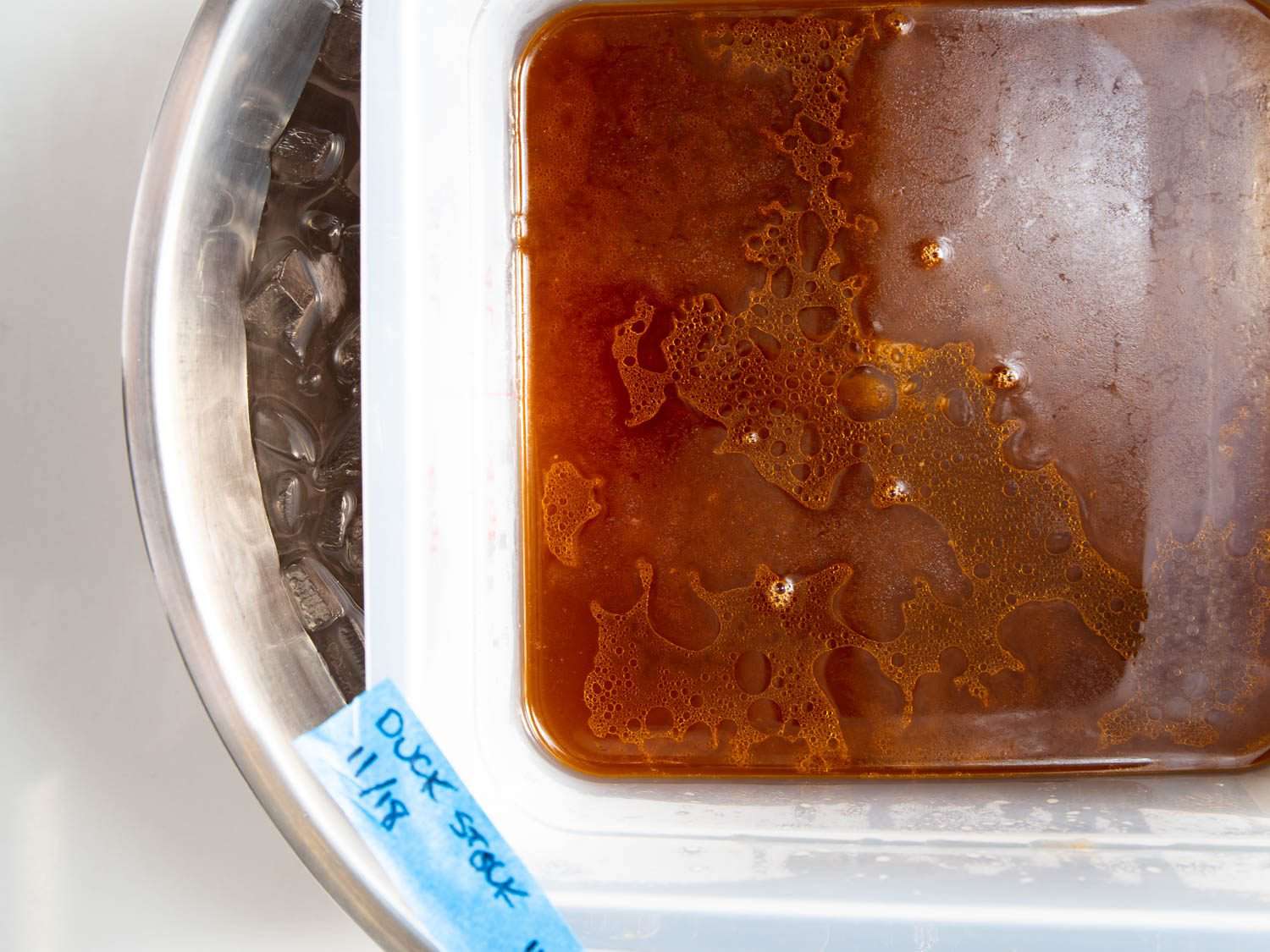 A container of duck stock set in an ice bath to rapidly cool.