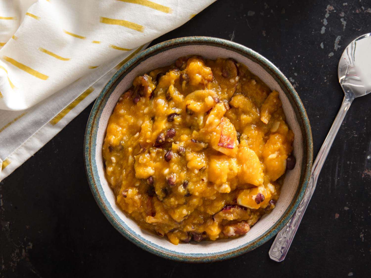 A bowl of hobak beombeok next to a spoon and a napkin. 