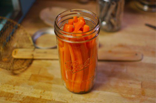 Carrot sticks are packed vertically in a canning jar.