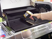 a person using an infrared thermometer to take the temperature of the griddle in the grill