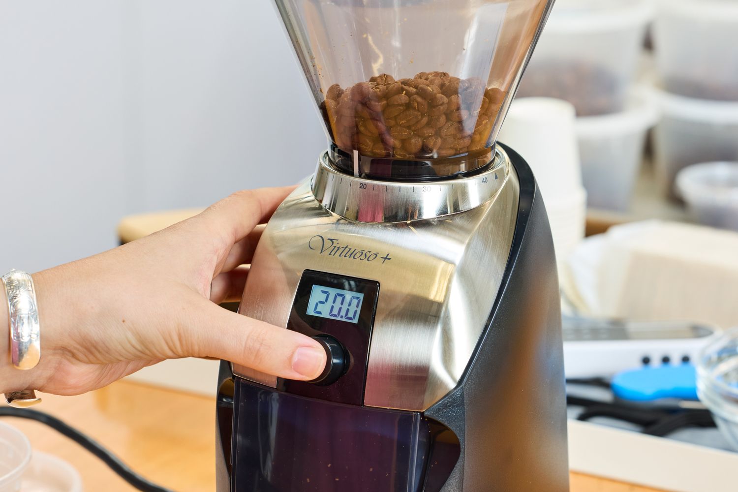 A person presses a button on the Baratza Virtuoso+ Conical Burr Coffee Grinder