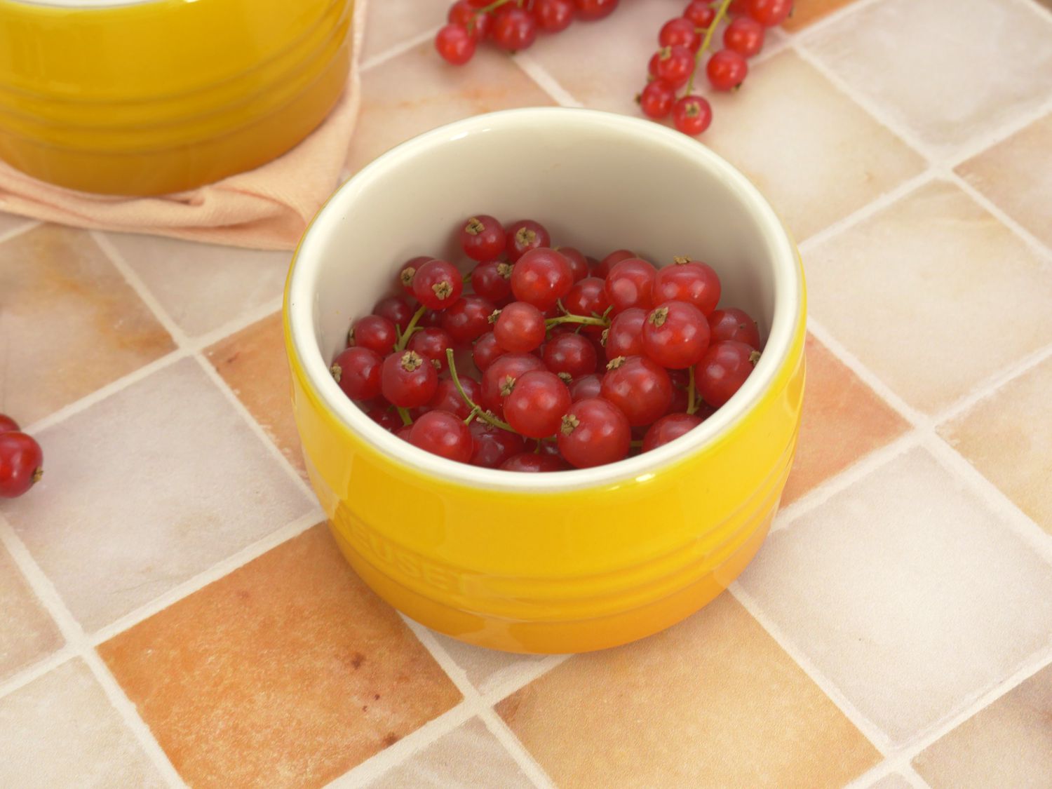 closeup of the le creuset ramekin on a marble tile surface with currants 