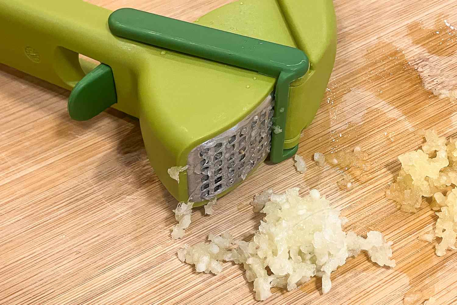 Garlic press with minced garlic on a cutting board