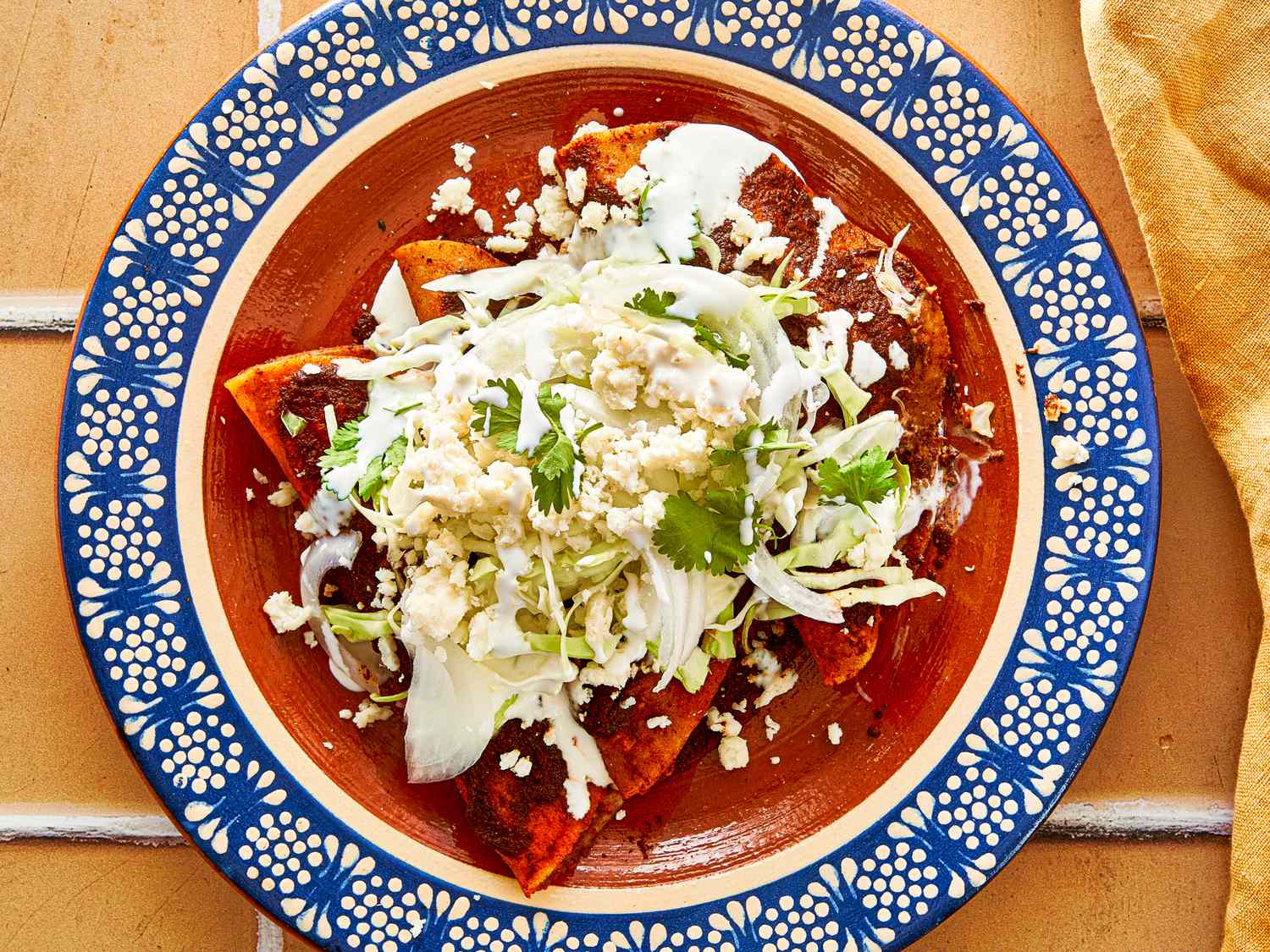 A plate of enchiladas topped with cheese and lettuce