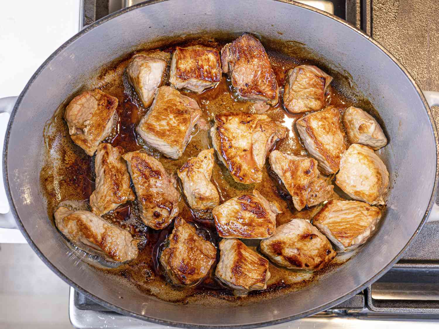 Overhead view of pork cooking in a dutch oven