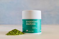 A container of Rishi Tea Everyday Matcha next to a pile of the powder