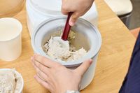 Two hands using a spatula to remove ice cream from the Cuisinart 1.5-Quart Ice Cream Maker
