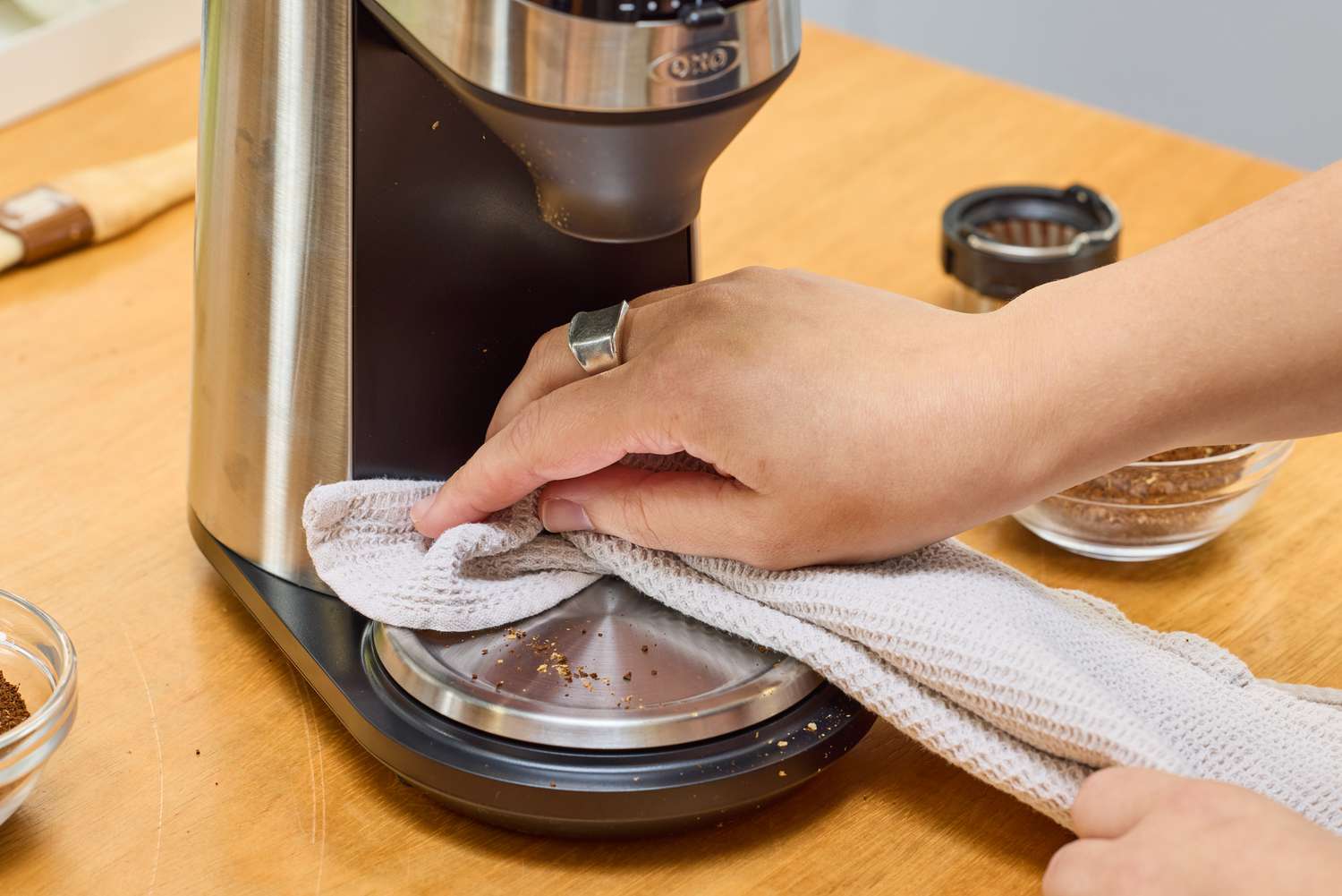 A person wipes down the OXO Brew Conical Burr Coffee Grinder With Integrated Scale