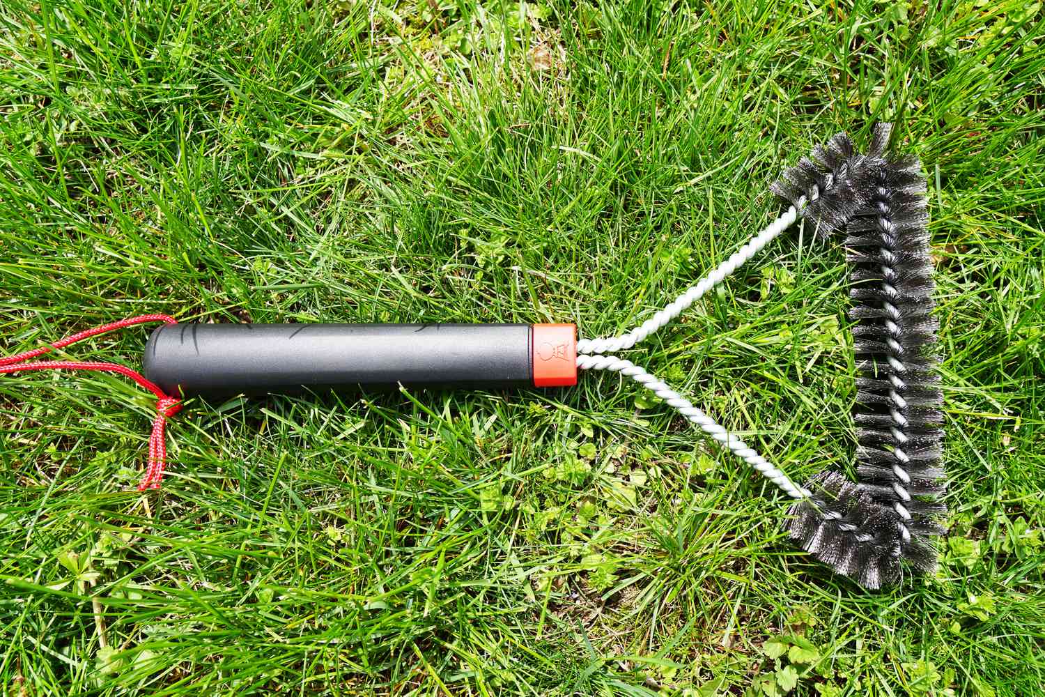 a weber grill brush laying on the grass
