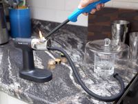 a hand lighting the breville polyscience smoker with a lighter