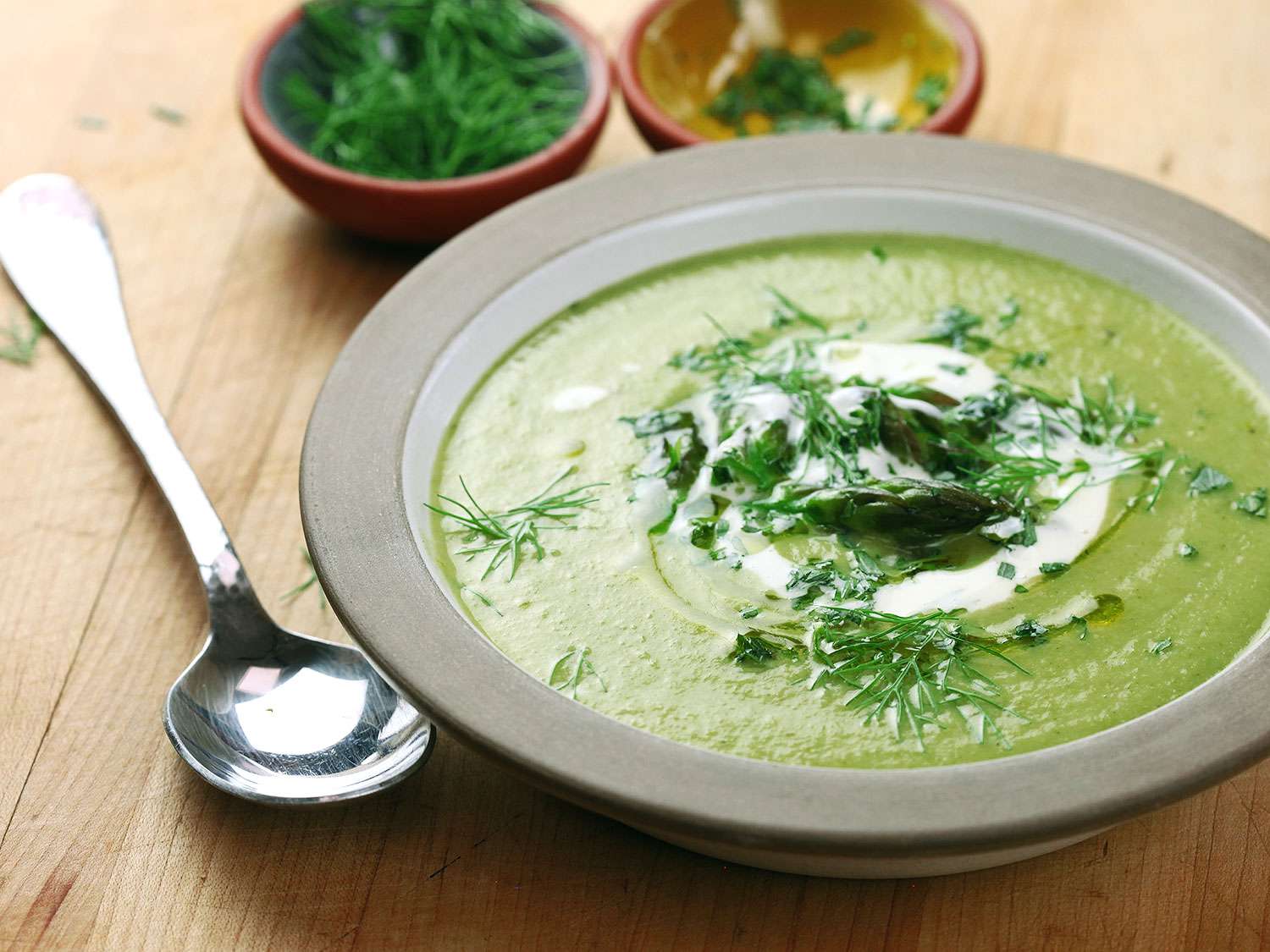  A bowl of creamy asparagus and tarragon soup and the garnishes of fennel fronds and chopped tarragon.