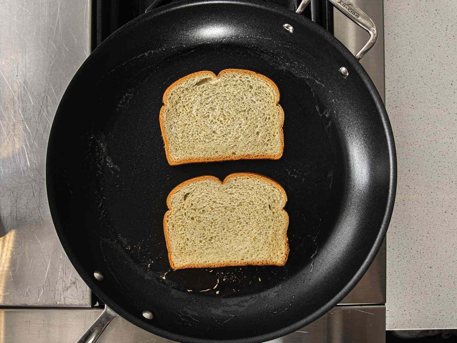 Overhead view of two pieces of bread in a pan with butter