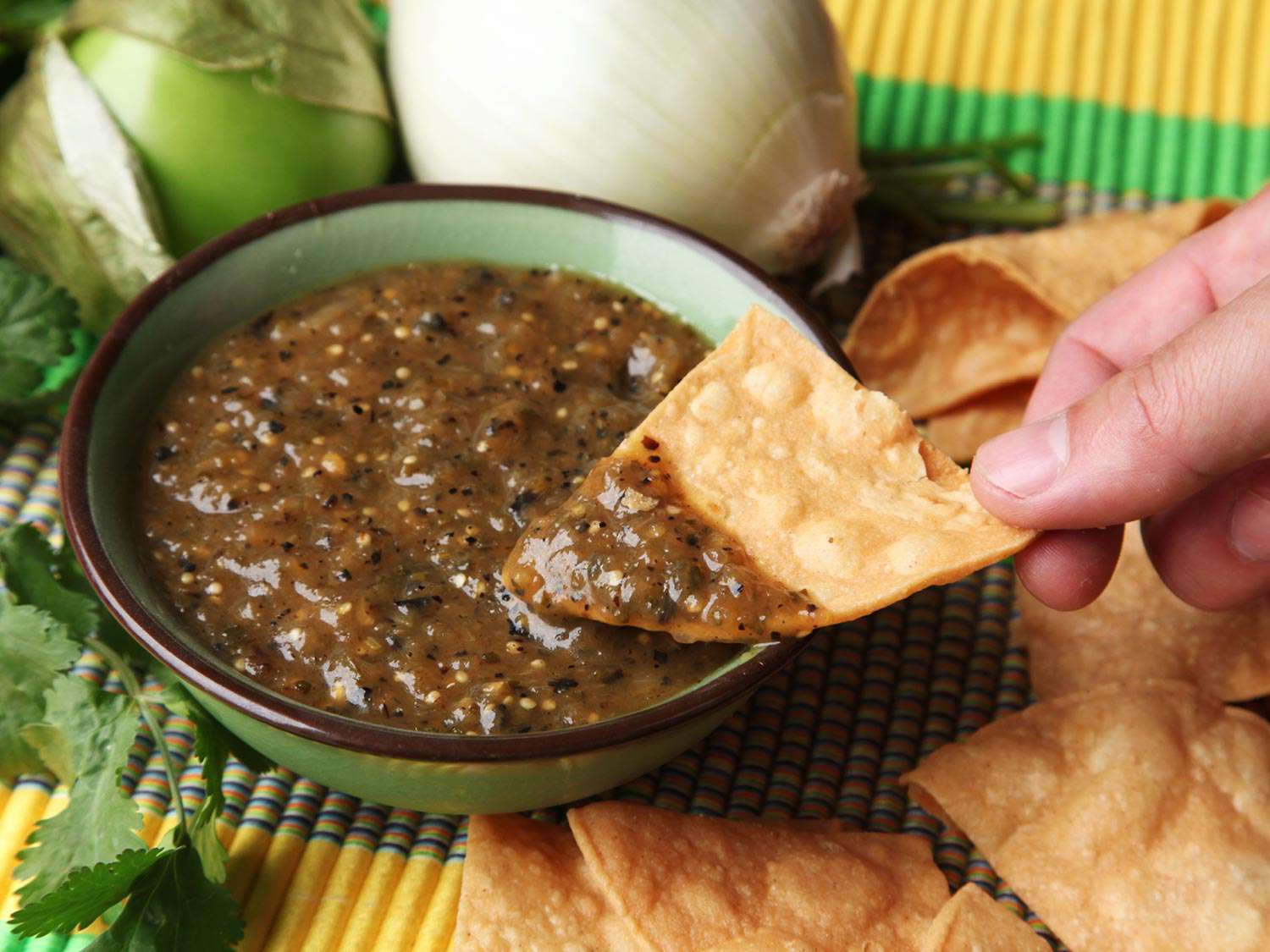 Dipping a tortilla chip into the charred salsa verde.