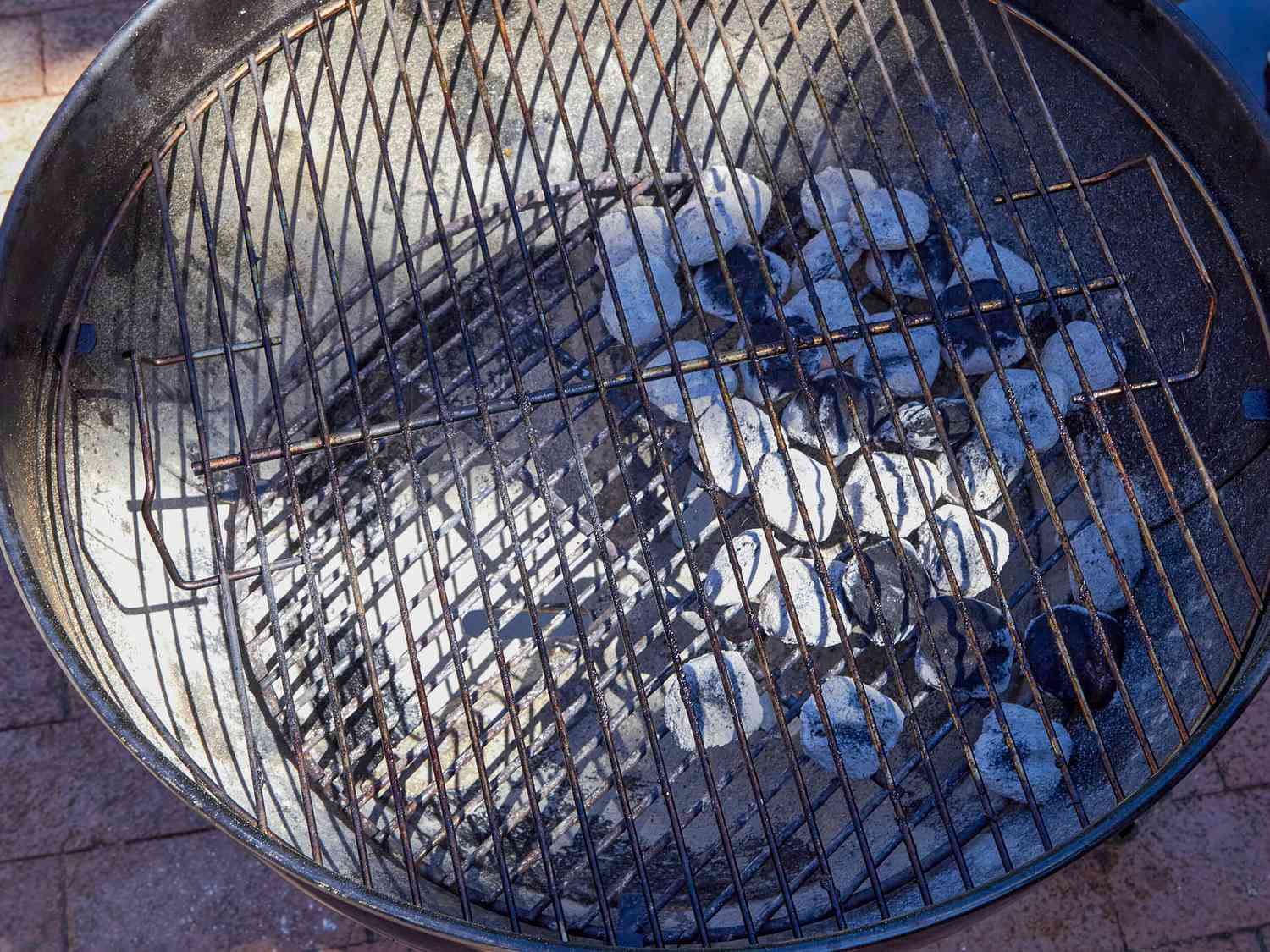 Charcoal grill with hot charcoal briquettes, grill grate above coals