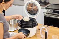 A person removes cooked rice from the Instant Pot 20 Cup Multigrain Cooker