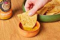 Person dipping chip into Tia Lupita Habanero Hot Sauce
